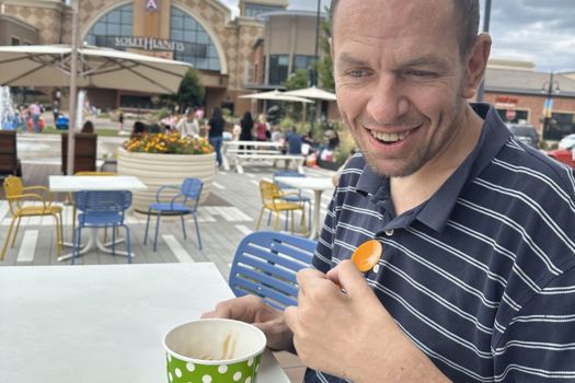 Michael S, GSF Client, pictured wearing a blue striped collar shirt eating ice cream outside the mall