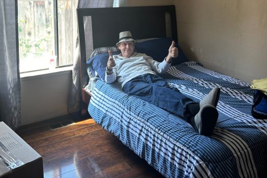 a person sitting on their bed giving the thumbs up