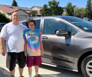 Two individuals standing in front of a car. Grace and her Father.