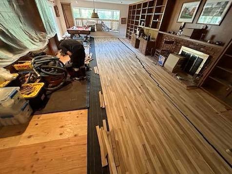 a person is working on a hardwood floor in a living room