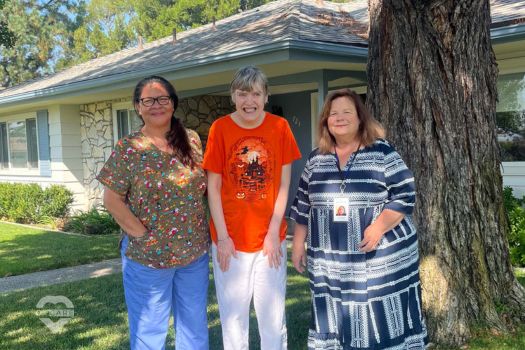 three people standing in front of a house