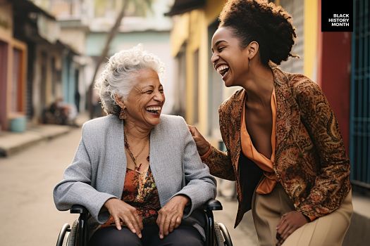 A woman in a wheelchair laughing with another woman