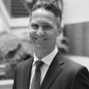 a black and white photo of Jeffrey Turrini in a suit and tie